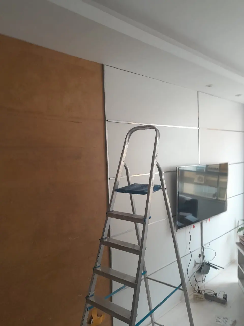 Painel de madeira sendo instalado com o apoio de uma escada